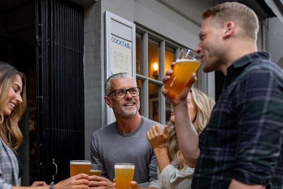 People smiling drinking beer outside a pub