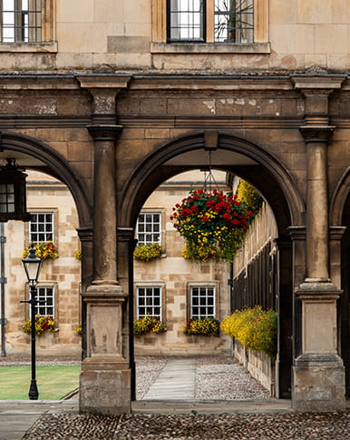View of flower baskets through arches of Cambridge University