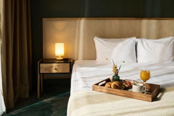 Image of a hotel bed with breakfast on a tray