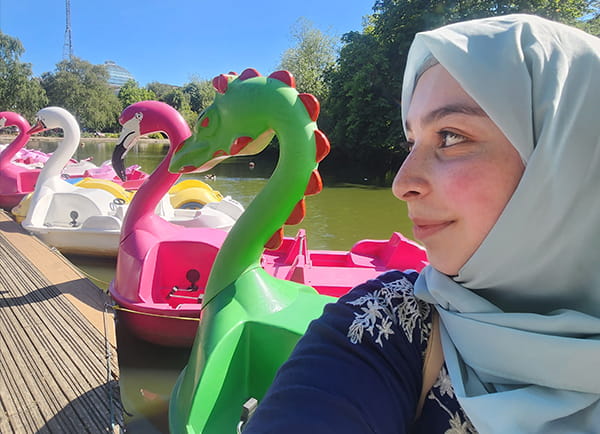 Close up of a girl with flamingo boats in the background