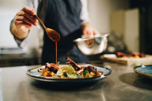 Chef pouring sauce on pork ribs in the kitchen stock photo