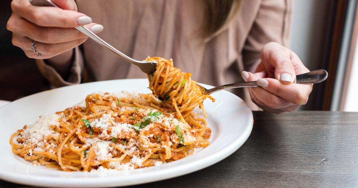 Woman eating spaghetti italian restaurant stock photo